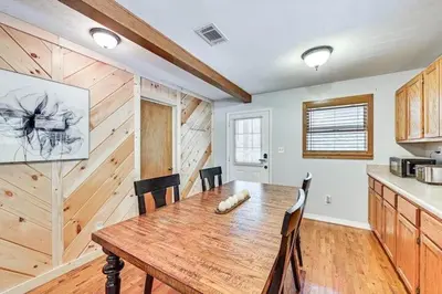 a dining room with a wooden table and a kitchen at The Best of Cave Run & Morehead! in Morehead