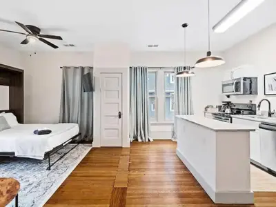 a white bedroom with a bed and a kitchen at Victorian Estates - Cute Stuido - Steps To Clinic in Cleveland