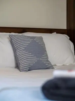 a gray pillow on a bed with white pillows at Victorian Estates - Cute Stuido - Steps To Clinic in Cleveland