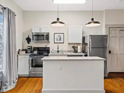 a kitchen with stainless steel appliances and white cabinets at Victorian Estates - Cute Stuido - Steps To Clinic in Cleveland
