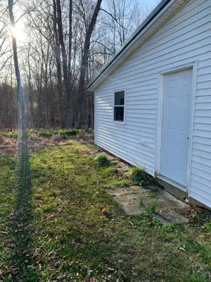 a white garage with a door on the side of a house at Country Getaway in Stewart