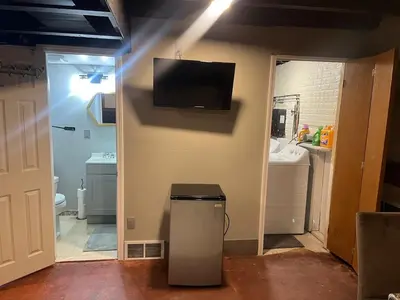 a bathroom with a trash can and a television on a wall at Modern Glass City Home in Toledo