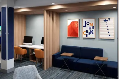 a lobby with a blue couch and a desk with a laptop at Holiday Inn Express & Suites Muncie Northwest by IHG in Muncie
