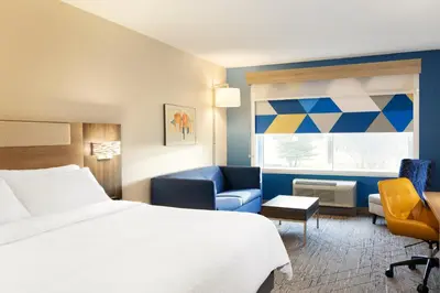 a hotel room with a bed and a chair and a window at Holiday Inn Express & Suites Muncie Northwest by IHG in Muncie