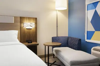 a room with a bed and a chair and a table at Holiday Inn Express & Suites Muncie Northwest by IHG in Muncie