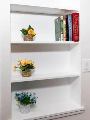 a white book shelf with flowers and books at Yellow Harmony in South Euclid