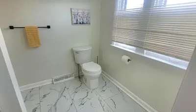a white bathroom with a toilet and a window at Yellow Harmony in South Euclid