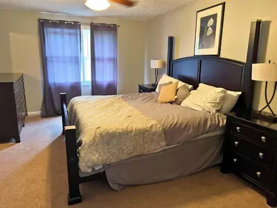 a bedroom with a large bed with a wooden headboard at Private Cul-de-Sac Oasis 4BR in Grove City