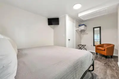 a white bedroom with a bed and a chair at NEW Renovated Near CLE - King Bed, Metropark & Firepit in Berea