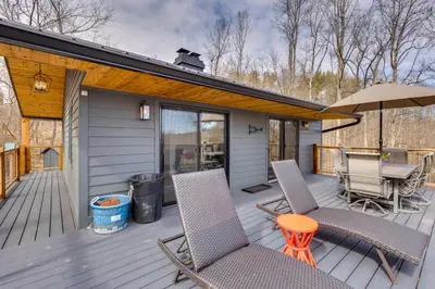 a deck with chairs and a table and an umbrella at 1 Mi to Marina Cabin with Views Near Atwood Lake! in Dellroy