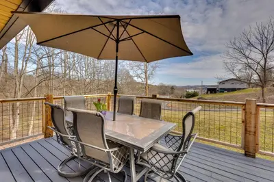 a table and chairs with an umbrella on a deck at 1 Mi to Marina Cabin with Views Near Atwood Lake! in Dellroy