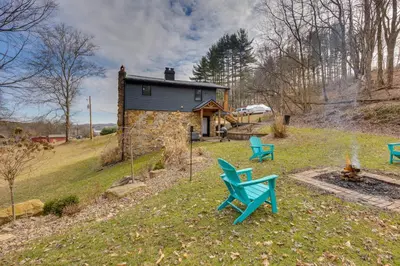 a stone house with blue chairs in the yard at 1 Mi to Marina Cabin with Views Near Atwood Lake! in Dellroy