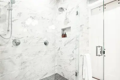 a bathroom with a shower with white marble walls at Luxury 4BR - Washington Park - Walk Everywhere in Cincinnati