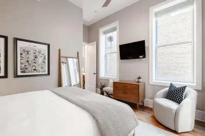 a bedroom with a bed and a chair and a tv at Luxury 4BR - Washington Park - Walk Everywhere in Cincinnati