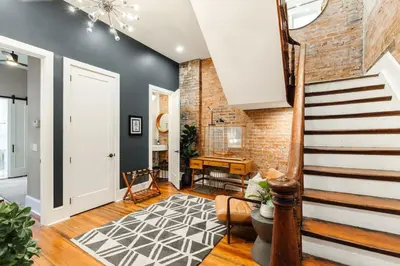 a living room with a staircase and a brick wall at Luxury 4BR - Washington Park - Walk Everywhere in Cincinnati