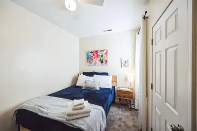 a bedroom with a blue bed in a white room at Charming Getaway on Ash St- Minutes from Cinci in Ludlow