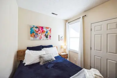 a bedroom with a blue bed and a window at Charming Getaway on Ash St- Minutes from Cinci in Ludlow