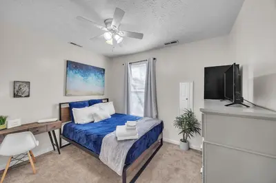a bedroom with a blue bed and a flat screen tv at Charming Getaway on Ash St- Minutes from Cinci in Ludlow