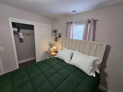 a bedroom with a bed with a green comforter at Cute New Const Wilmington Ranch in Wilmington