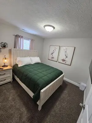 a bedroom with a bed with a green blanket at Cute New Const Wilmington Ranch in Wilmington
