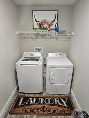 a laundry room with a washer and dryer and a cow picture at Cute New Const Wilmington Ranch in Wilmington