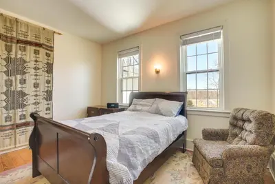 a bedroom with a bed and a chair and windows at Spacious and Updated Farmhouse in Yellow Springs in Fairborn