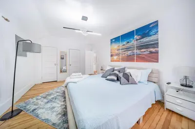 a white bedroom with a large bed and a blue rug at Kenmore Akron 3 bedroom 1 bath in Akron