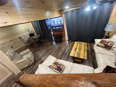 a living room with a couch and a table and a tv at Cabin in the treetops! in Lancaster