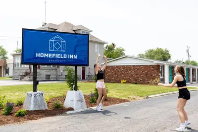 two girls playing volleyball under a sign in front of a house at HomeField Inn in Sandusky