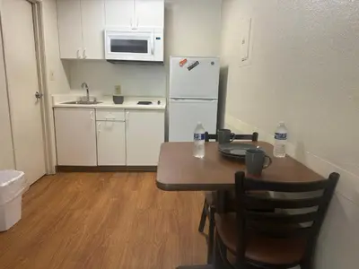 a small kitchen with a table and a refrigerator at Siegel Select Cincinnati Sharonville in Cincinnati