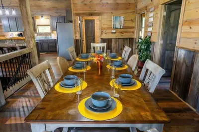 a dining room with a wooden table with yellow chargers at Serenity Ridge- Scenic Luxury Log Estate Getaway in McArthur