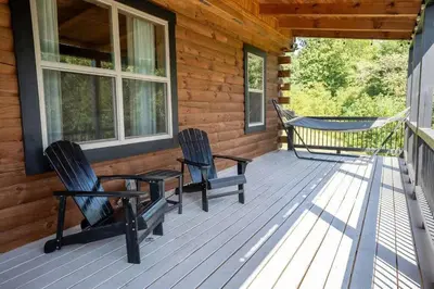 two chairs and a hammock on the porch of a cabin at Serenity Ridge- Scenic Luxury Log Estate Getaway in McArthur