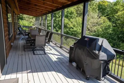 a deck with chairs and a grill on a house at Serenity Ridge- Scenic Luxury Log Estate Getaway in McArthur