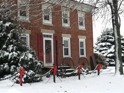 a red brick house with a christmas tree in the snow at Charming Cabin Rental with a Hot Tub near Cedar Point and Lake Erie in Ohio in Bellevue