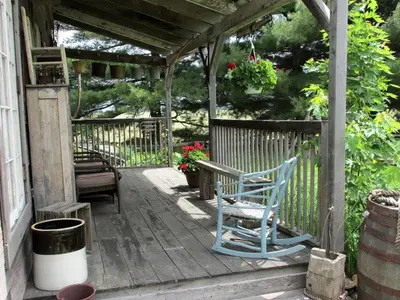 a porch with a blue rocking chair and a pergola at Charming Cabin Rental with a Hot Tub near Cedar Point and Lake Erie in Ohio in Bellevue