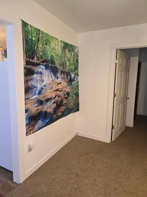a painting of a waterfall on a wall in a room at The Happy Place in Glouster