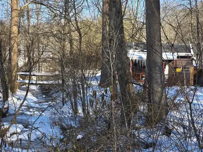 a snow covered yard with trees and a house at The Happy Place in Glouster