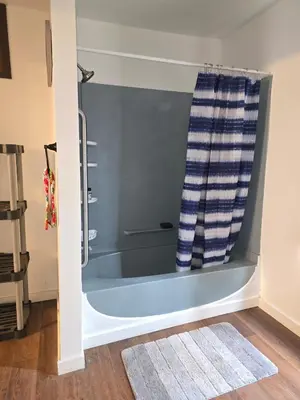 a bathtub in a bathroom with a blue shower curtain at The Happy Place in Glouster