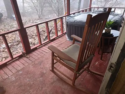 a rocking chair sitting on a porch in the snow at The Happy Place in Glouster