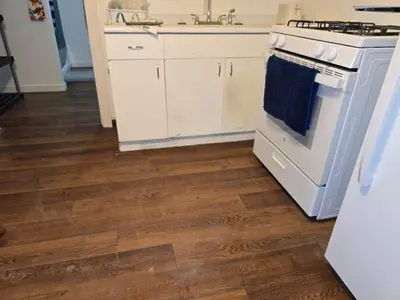 a kitchen with white appliances and wooden floors at The Happy Place in Glouster