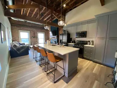a kitchen with a large white island with bar stools at Condo in OTR, Pendleton Art District in Cincinnati