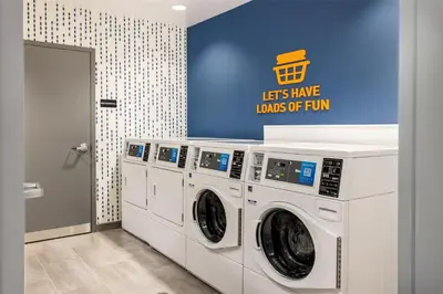 a laundry room with three washing machines and a sign at Home2 Suites By Hilton Dry Ridge in Dry Ridge