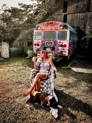 a woman sitting next to a dog next to an old bus at Cozy Hot Tub “Love Bus” near Augusta, Kentucky in Germantown