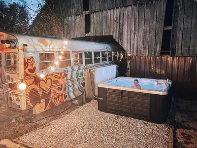 a person in a hot tub next to an old bus at Cozy Hot Tub “Love Bus” near Augusta, Kentucky in Germantown