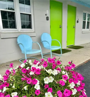 two blue chairs sitting outside of a house with flowers at The Springs Motel