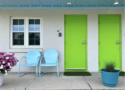 two chairs sitting outside of a house with green doors at The Springs Motel