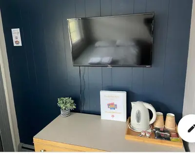 a tv hanging on a blue wall with a table at The Springs Motel