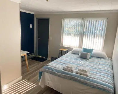a bedroom with a large bed with blue and white sheets at The Springs Motel
