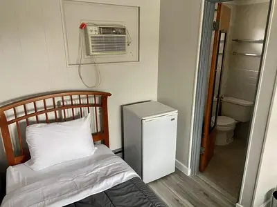 a bedroom with a bed and a air conditioner at The Springs Motel