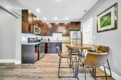 a kitchen with wooden cabinets and a table and chairs at Cle Suites 1BR 1BA 5 min Walk to Cle Clinic Unit 6 in Cleveland